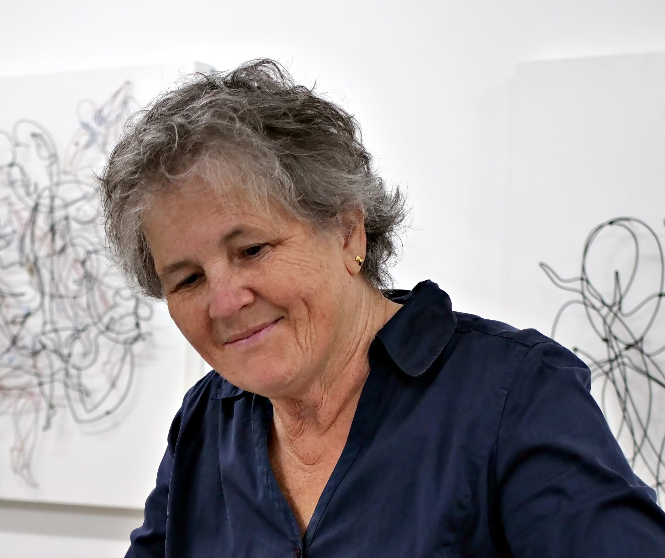 Pamela Merory Dernham in front of a steel wire artwork
